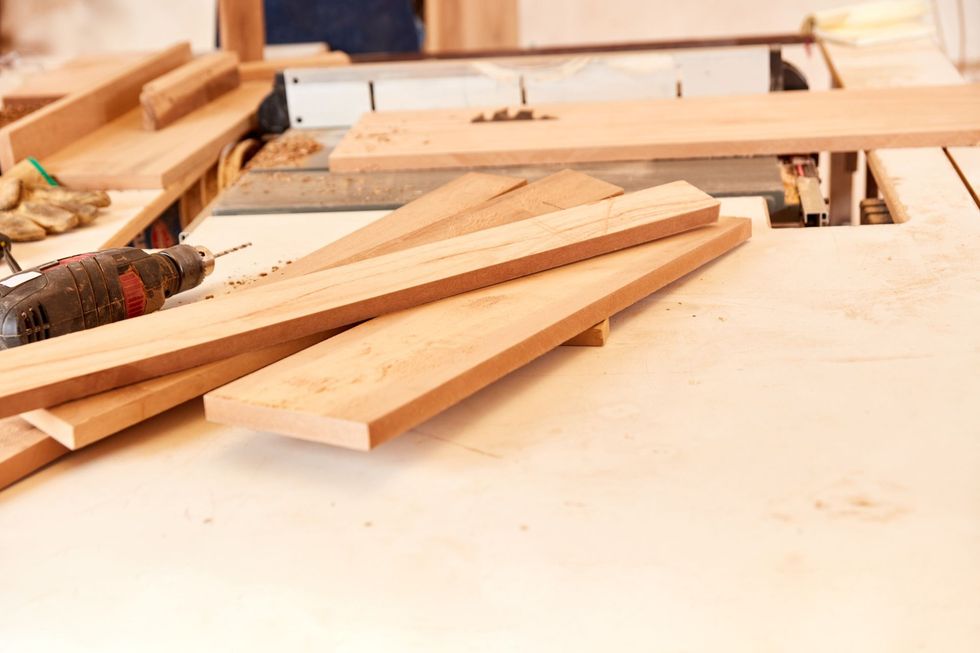 Un taladro está sobre una mesa al lado de una pila de madera.