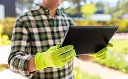 Un hombre que lleva guantes verdes sostiene una tableta.
