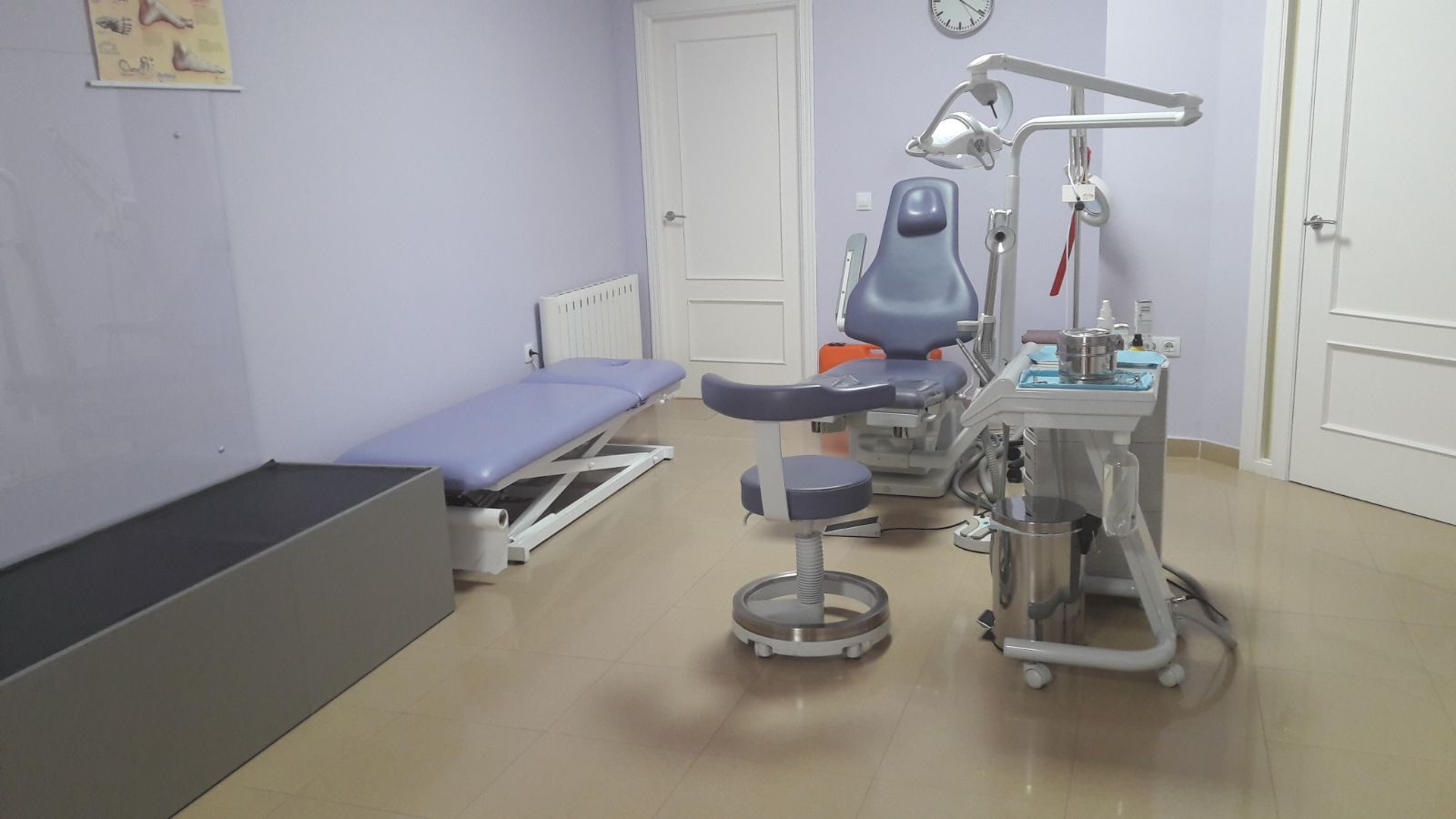 Un consultorio dental con un sillón dental y una cama.