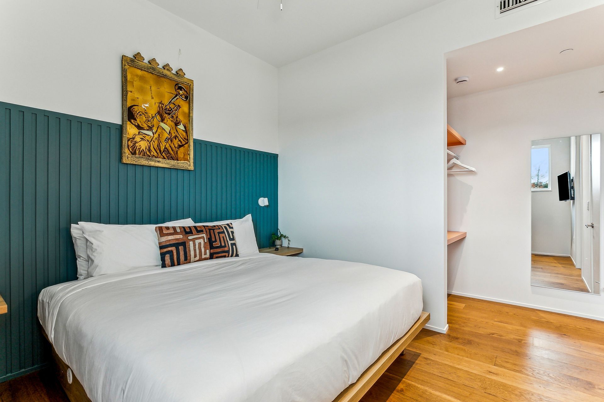 Bedroom with a king bed, teal accent wall, artwork, and closet.