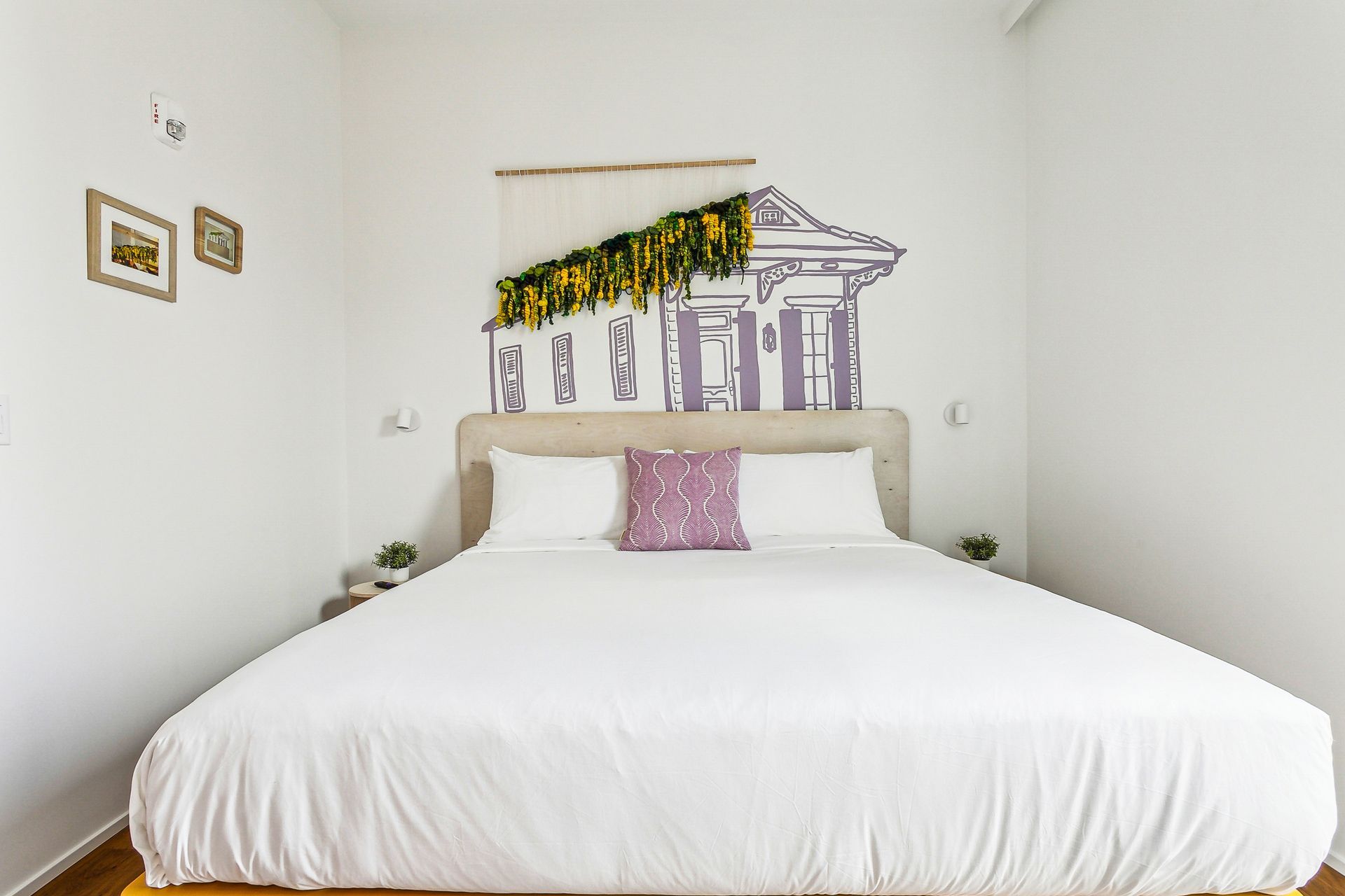 Bedroom with large bed, white bedding, and wall art of a building with trailing greenery.