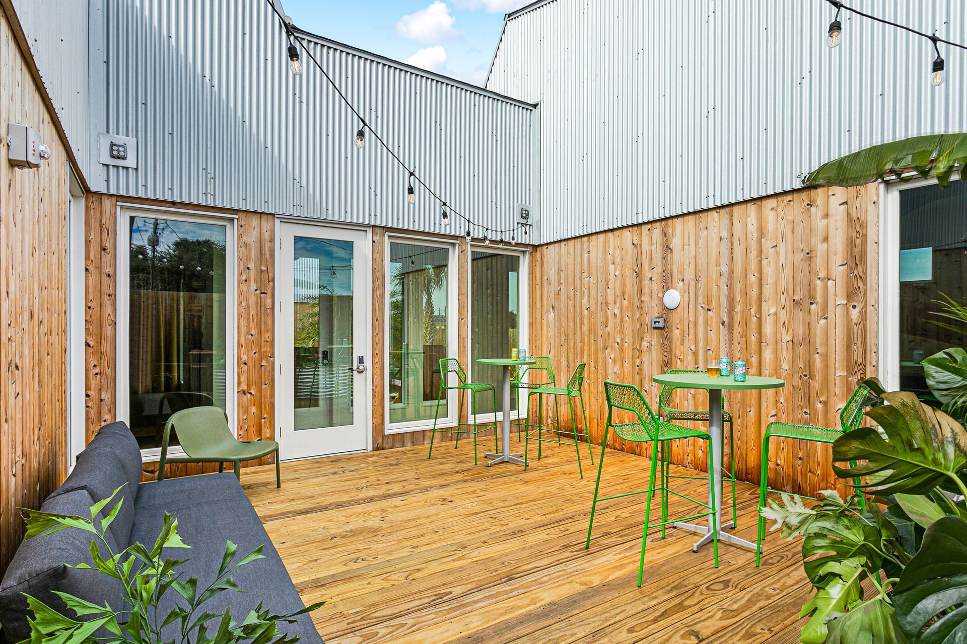 Outdoor patio with green chairs, wooden deck, and metal walls.