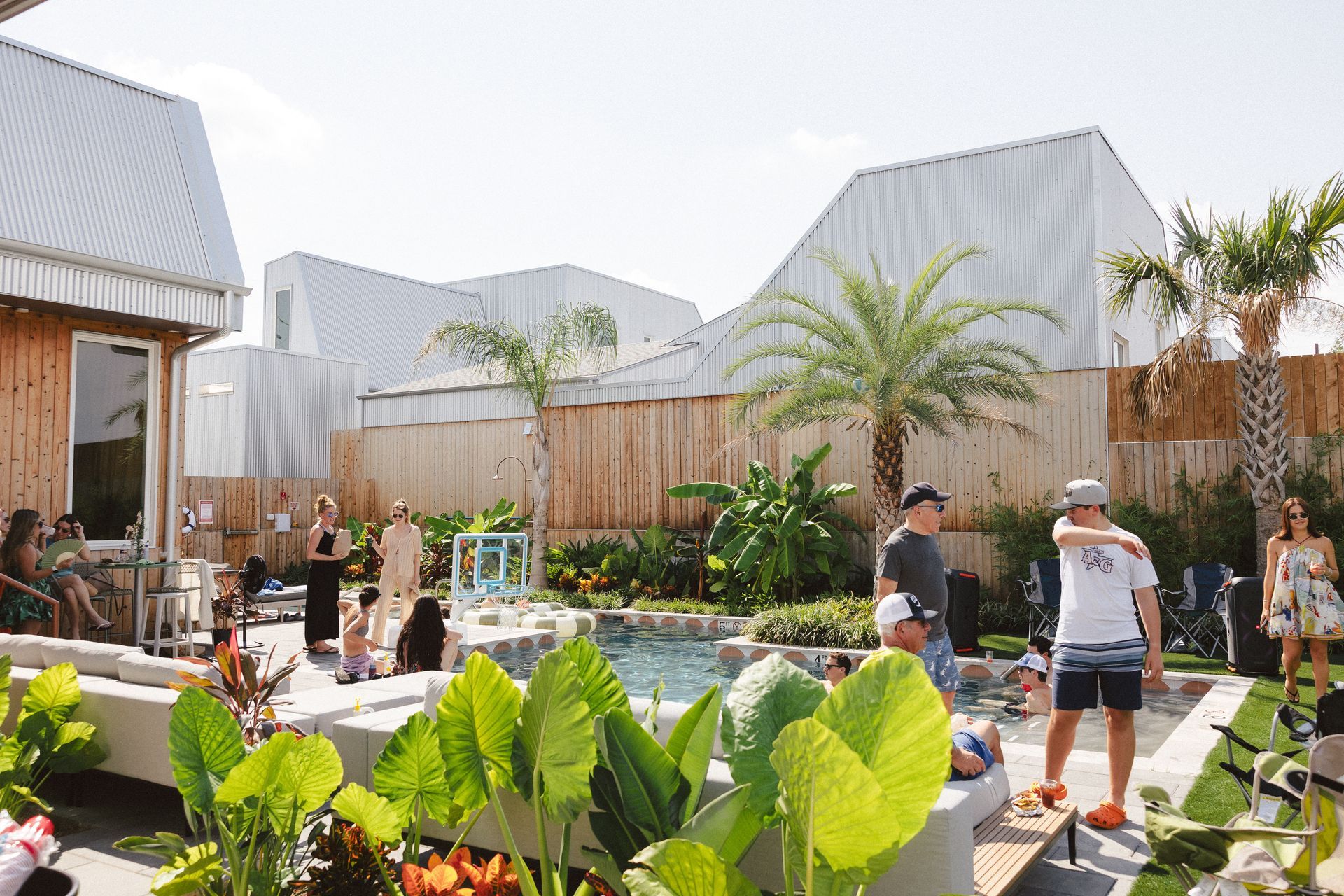 People practicing with small boards in a sunny courtyard garden with palm trees and modern buildings