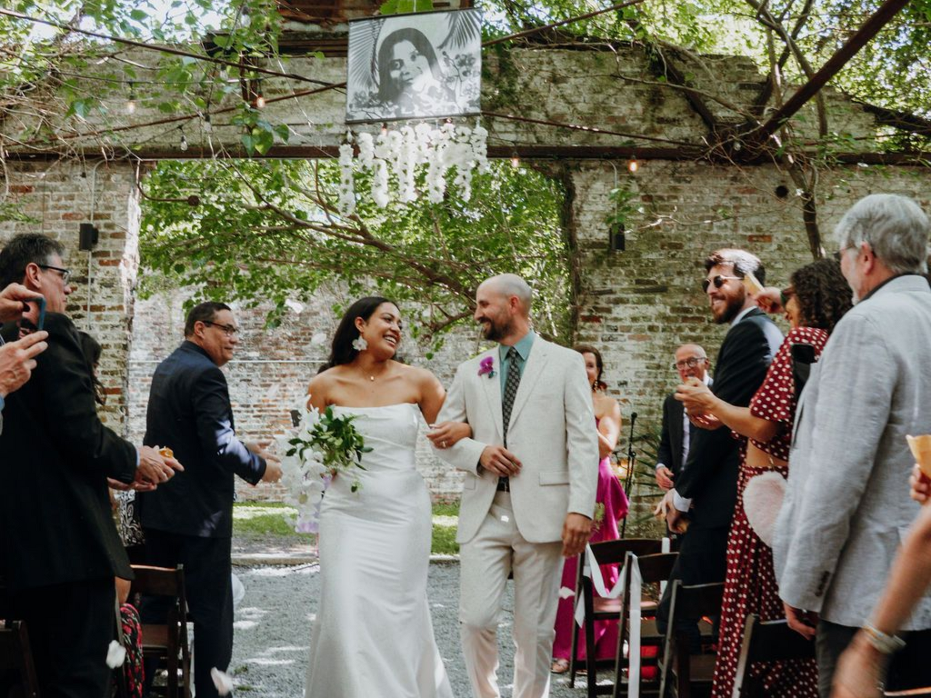 Wedding couple holding hands in an outdoor garden ceremony with guests watching
