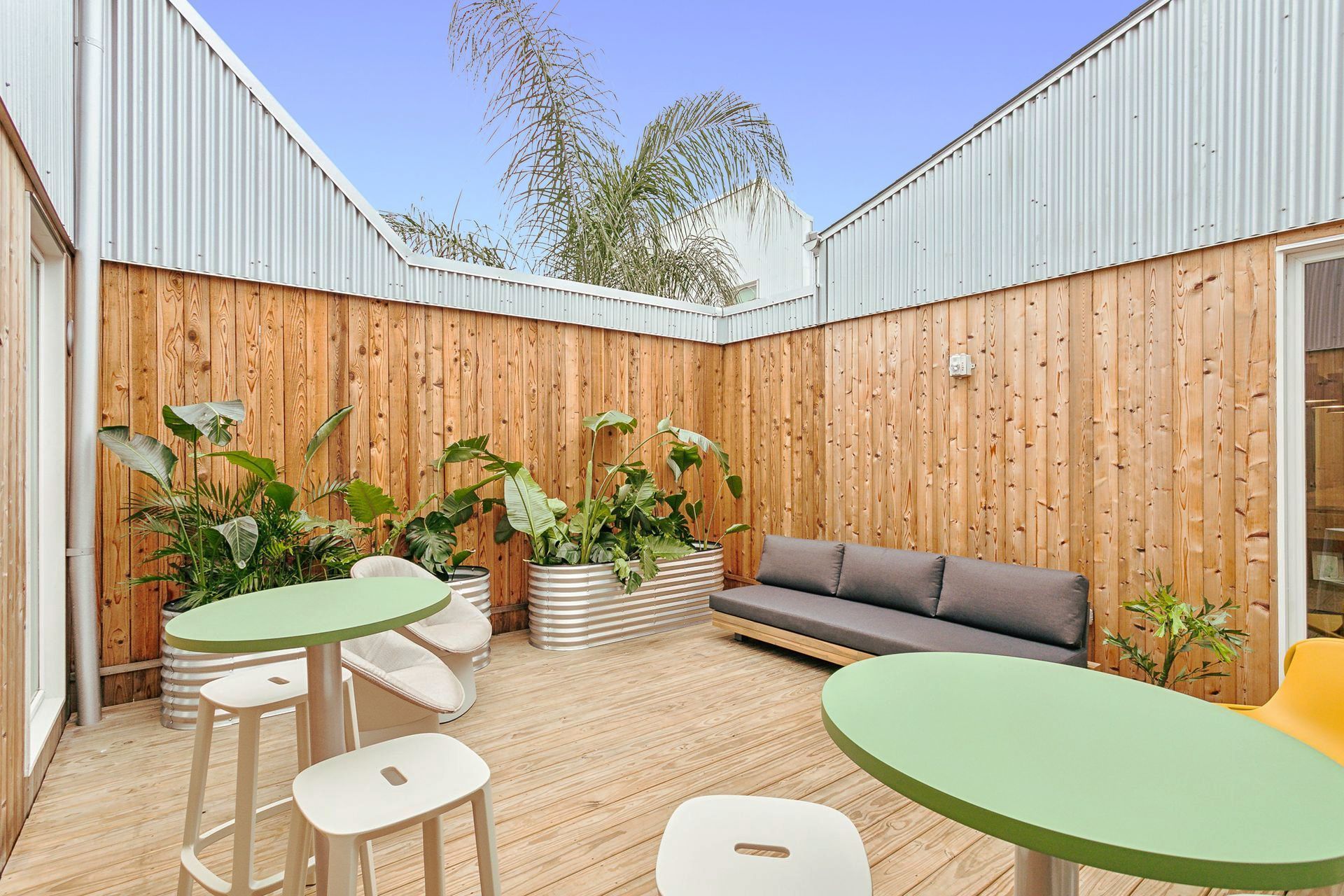 Outdoor courtyard with wood walls, gravel floor, furniture, and plants.