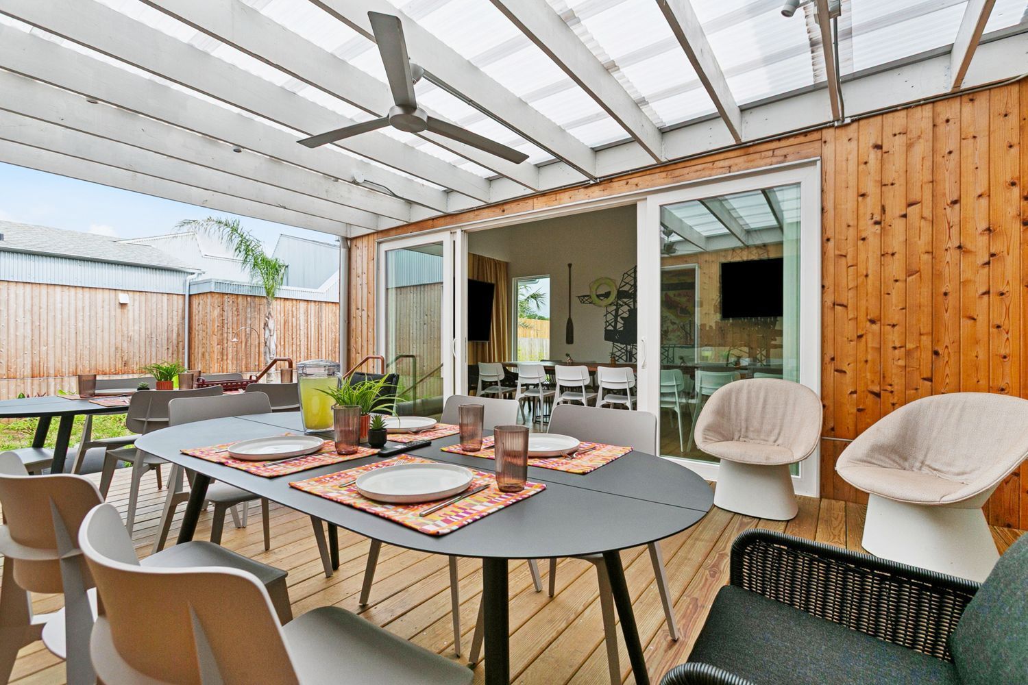 Outdoor dining area with table, chairs, and sliding glass doors leading to a house.