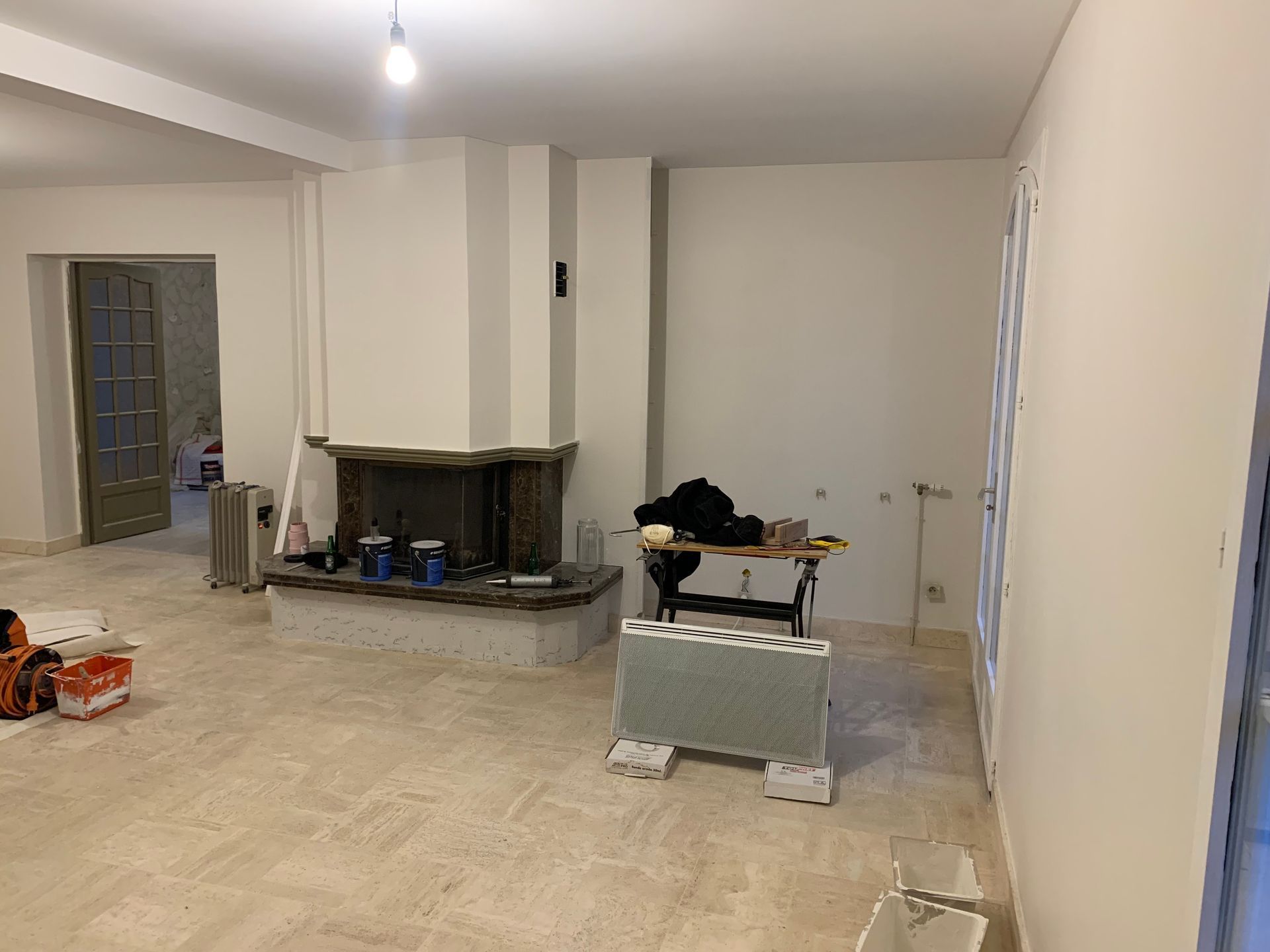 Salon après les travaux de peinture intérieure avec murs en pierre peints en blanc