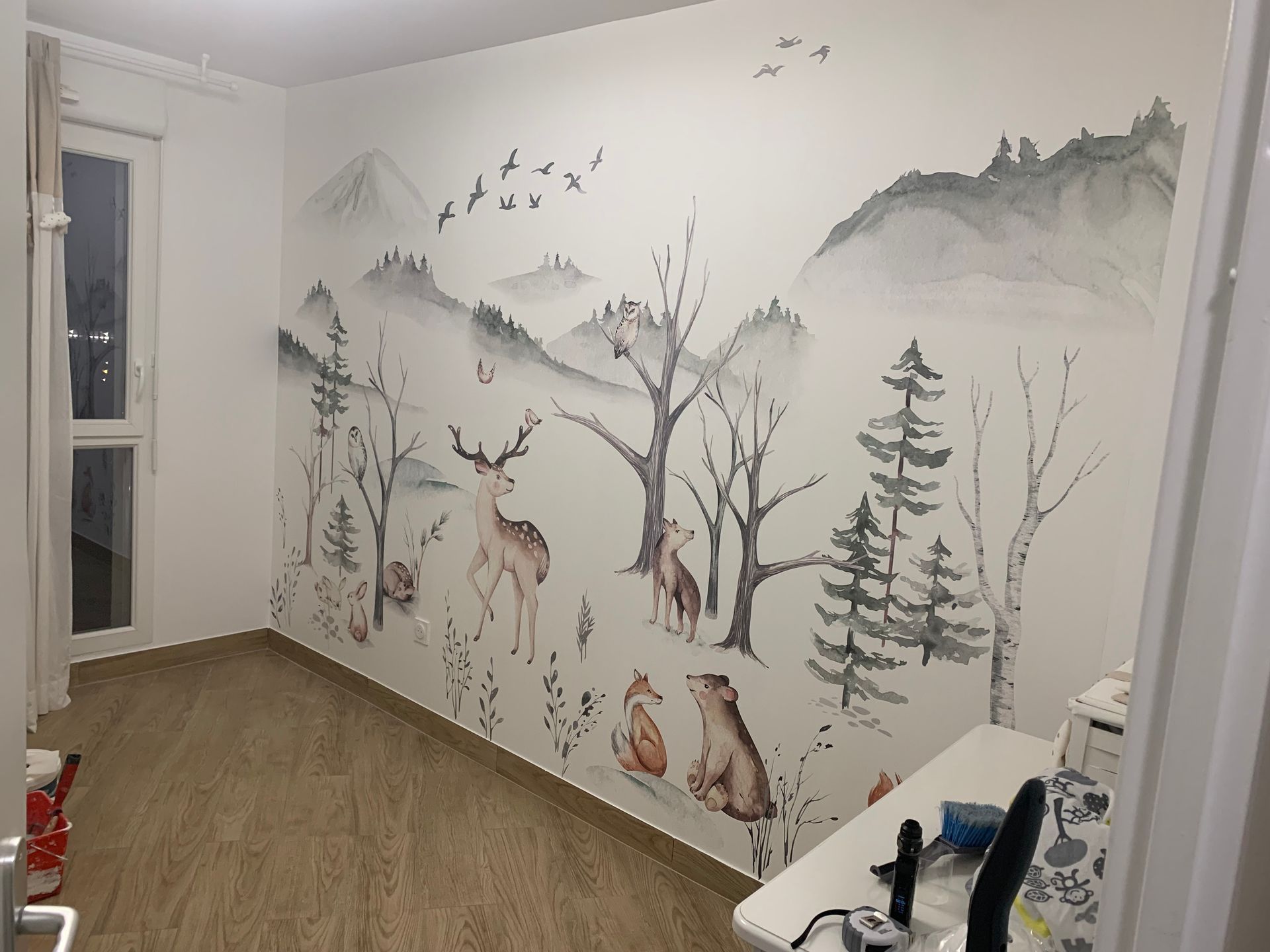 Mur de chambre d'enfant après notre intervention, avec un papier peint représentant des animaux de la forêt