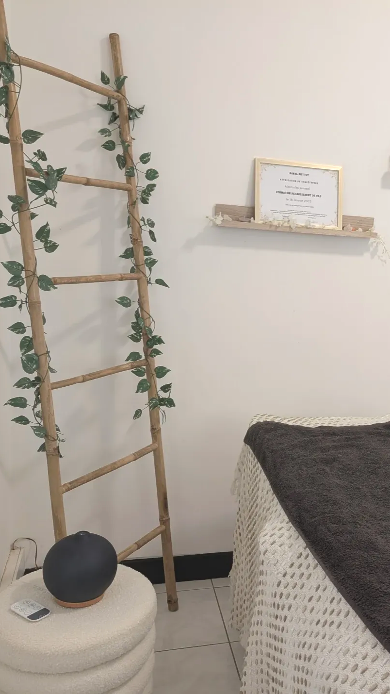 Une échelle en bois ornée de fausse verdure, une étagère décorative avec un papier encadré et un lit recouvert d'une couverture sombre.