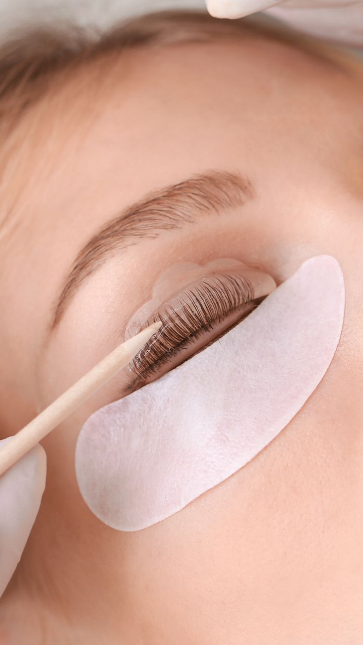 Une personne recevant un rehaussement de cils avec patchs pour les yeux en institut.