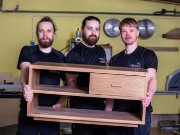 Taipuu Woodworks puuartesaanit pitelemässä puista hyllyä
