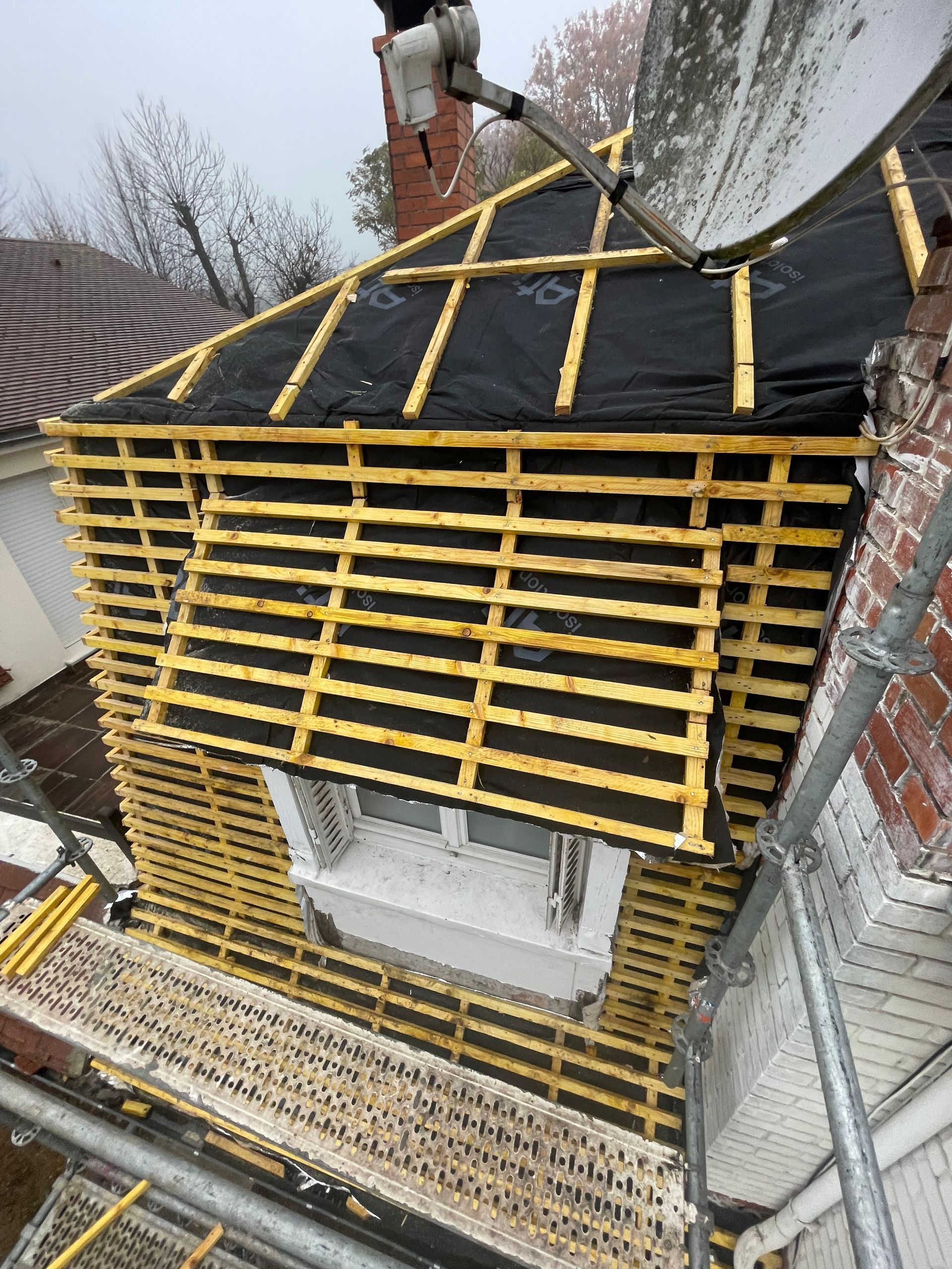 Une charpente dénudée avec un échafaudage installé sur la façade