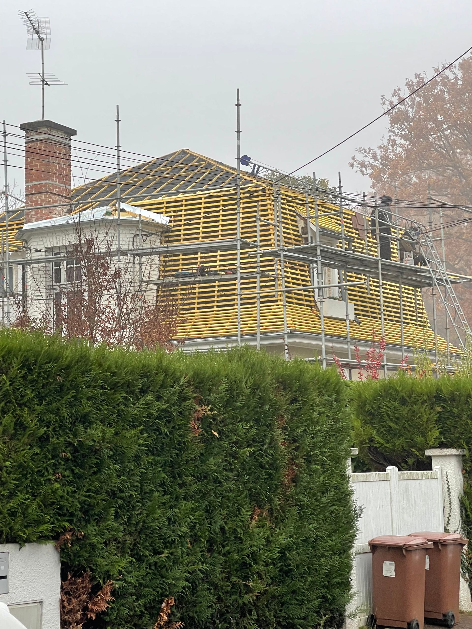 Un chantier de couverture en cours avec un grand échafaudage autour du bâtiment