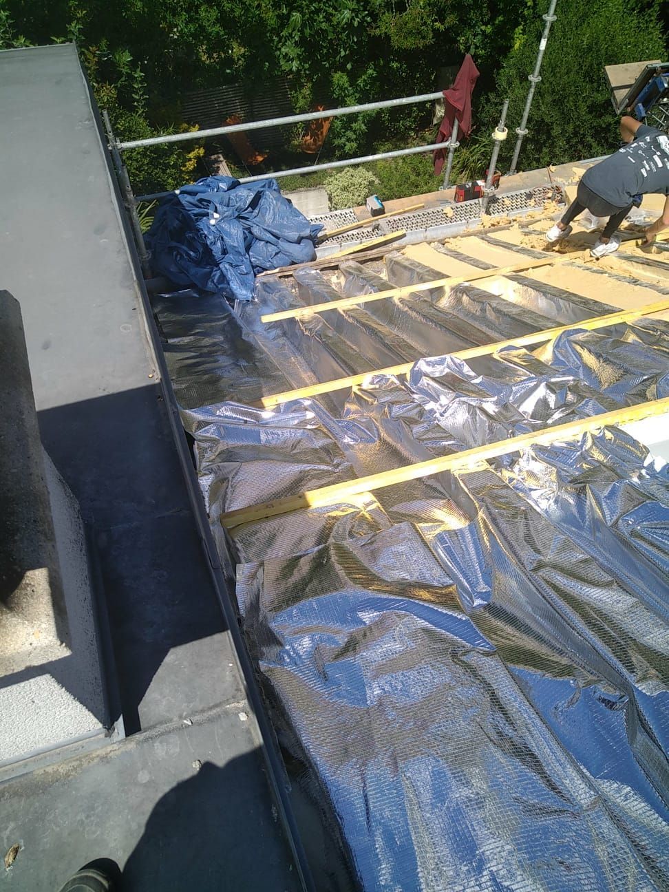 Des artisans en train de poser l'isolation d'un toit