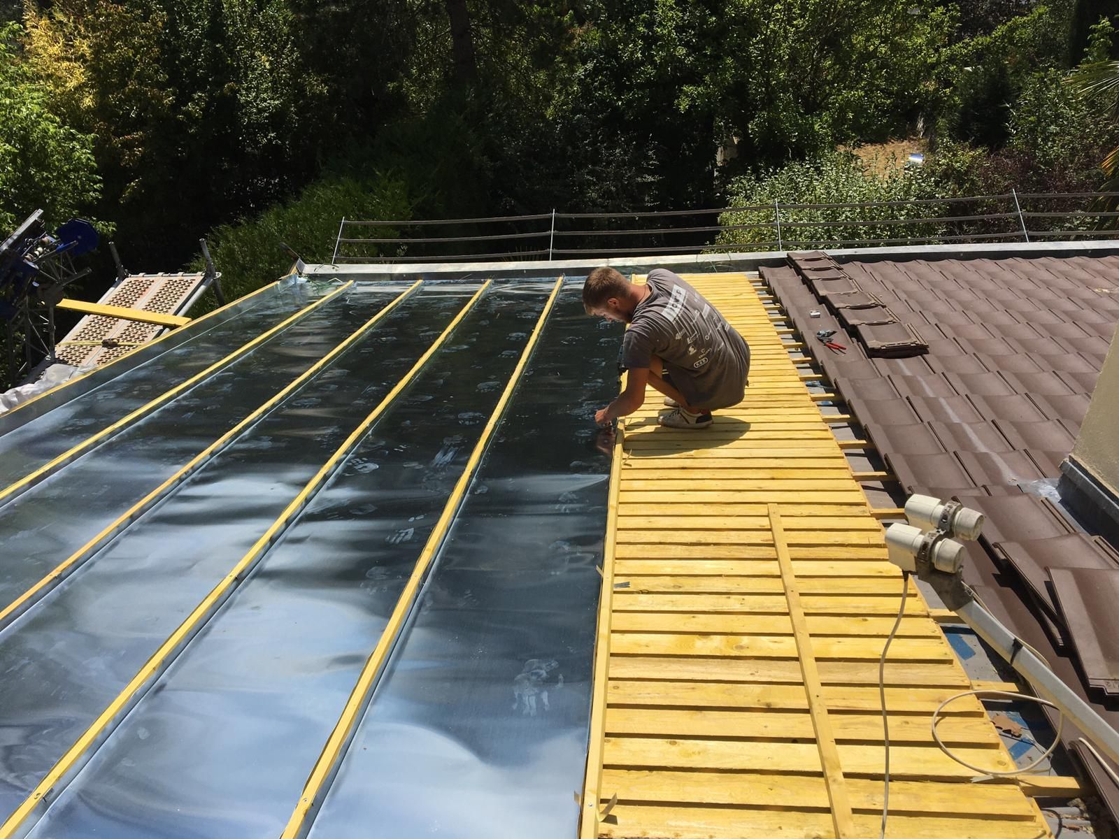 Un artisan couvreur en train d'installer l'isolation sur la charpente d'un toit-terrasse