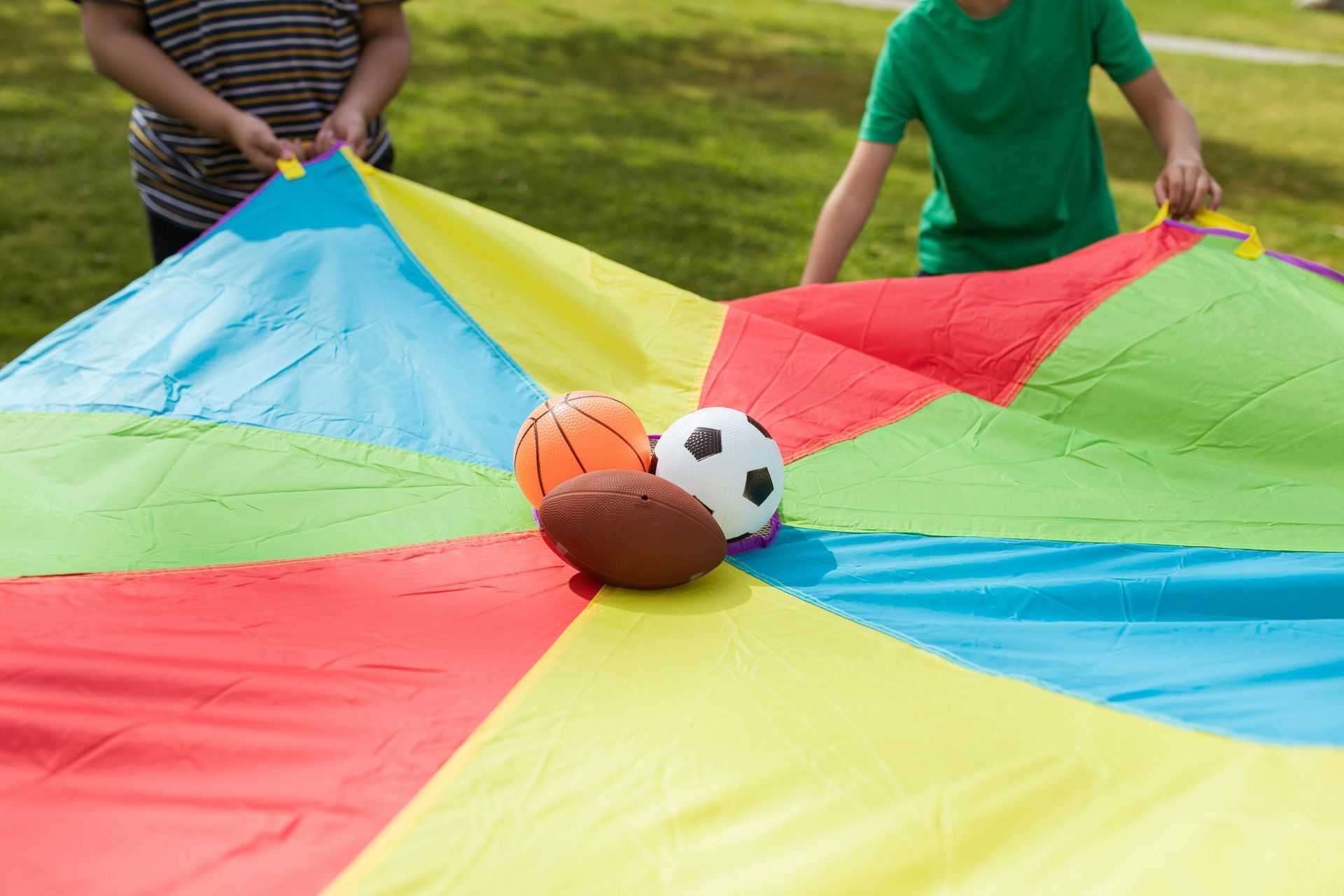 Niños y adultos en una sala de juegos de colores brillantes. Una maestra sonríe mientras otros se sientan y se quedan de pie