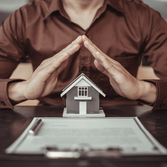 Mains posées sur une maquette de maison