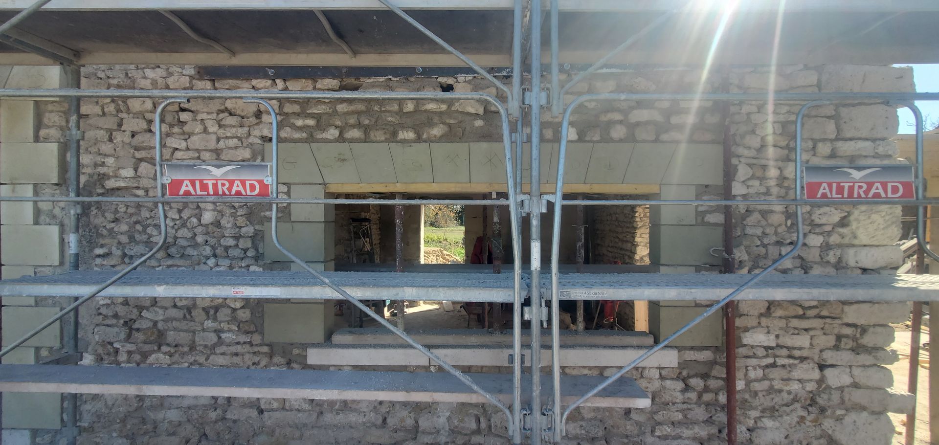 Échafaudage devant un mur en pierre.