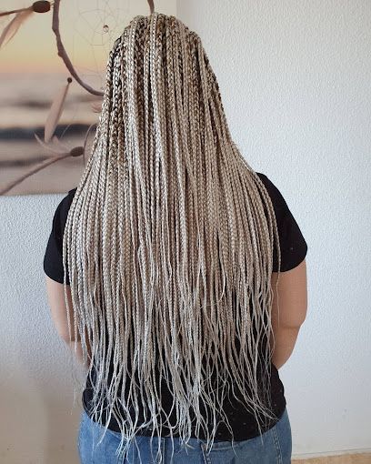 Una mujer con trenzas en el pelo está parada frente a una pintura.