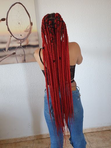 Una mujer con largas trenzas rojas está parada frente a un atrapasueños.