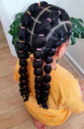 Una niña con trenzas y gomas en el pelo.