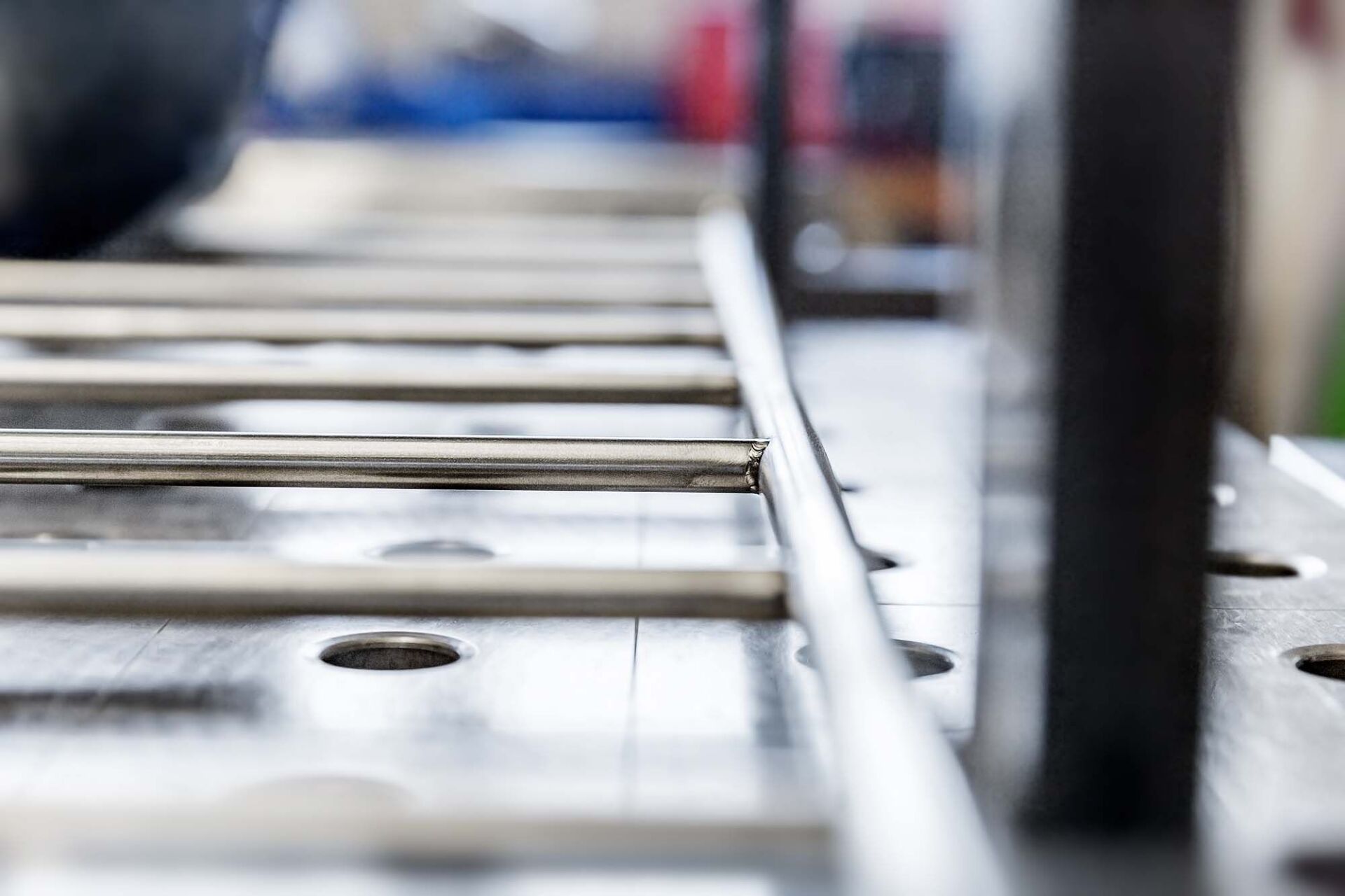 Metallstangen werden von einer Maschine gebogen. Nahaufnahme des Biegevorgangs auf einem Werkstatttisch.