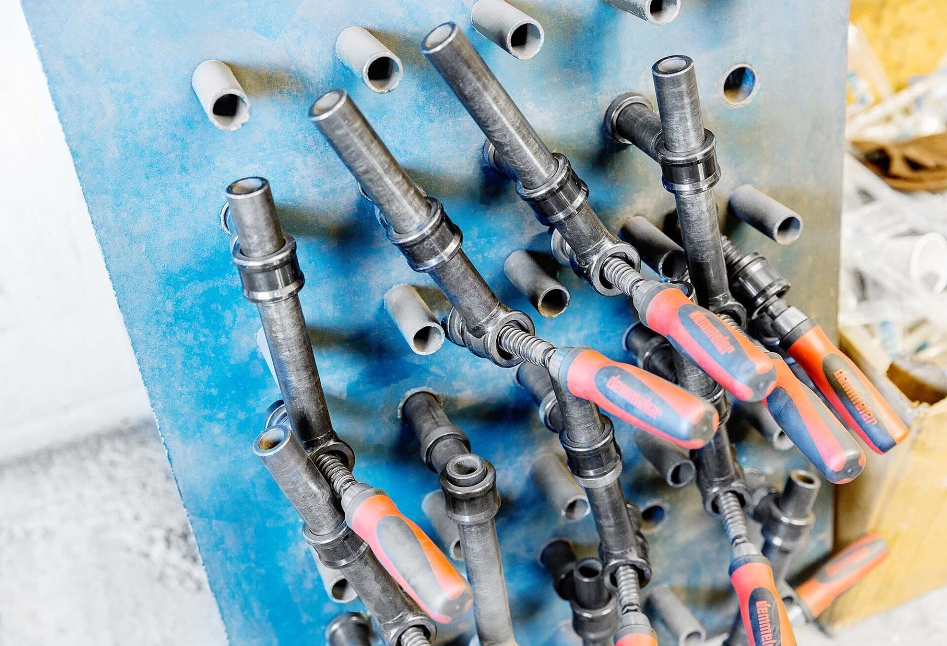 Blaues Brett mit mehreren Metallwerkzeugen mit farbigen Griffen.