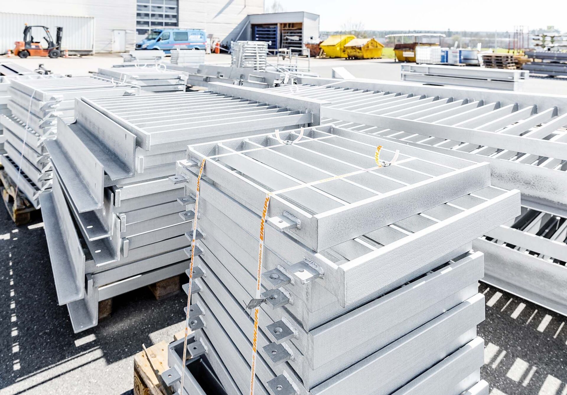 Stapel von verzinkten Stahlgitterrosten und Bauteilen im Freien.