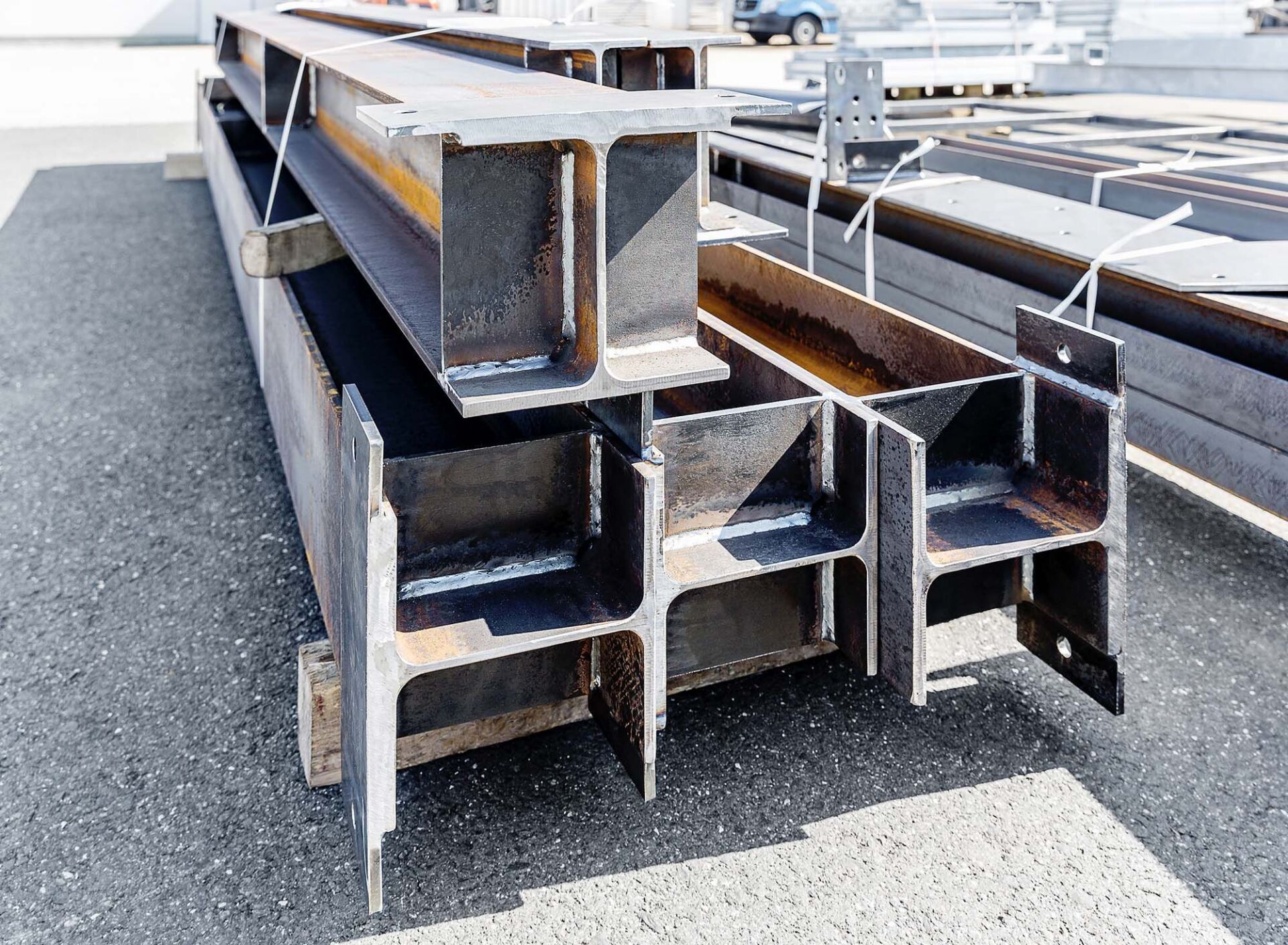 Stahlträger, die an einem sonnigen Tag im Freien auf Holzstützen gestapelt sind.