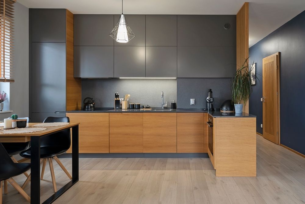 Cocina moderna con gabinetes superiores grises, gabinetes inferiores de madera y una isla de madera.