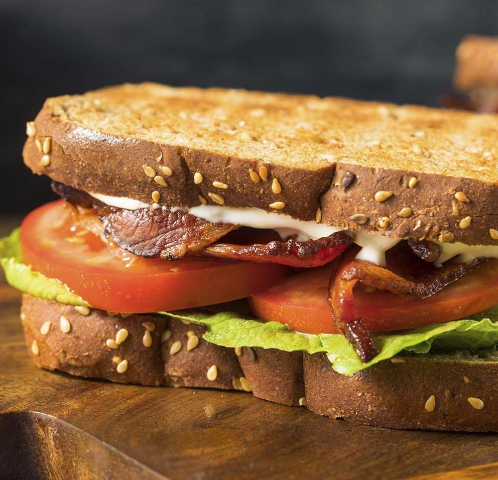 Un primer plano de un sándwich en una tabla de cortar de madera.
