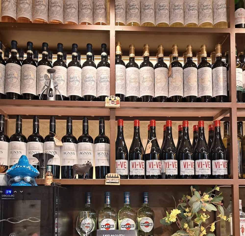Un estante lleno de botellas de vino, incluyendo vi-ve-ve-ve