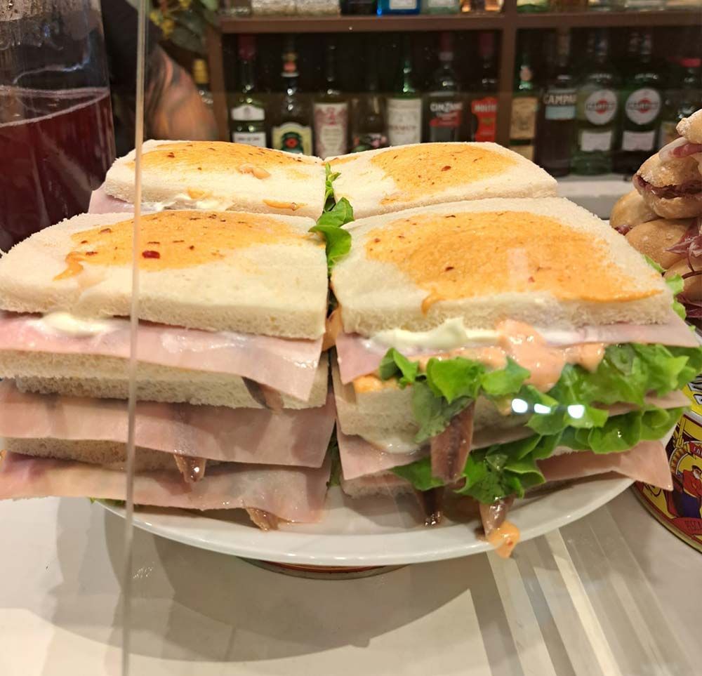 Un sándwich con jamón y lechuga se apila uno encima del otro en un plato.
