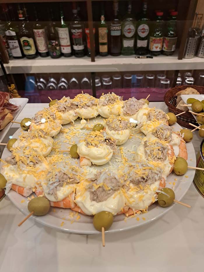 Un plato de comida con aceitunas en palitos sobre una mesa.