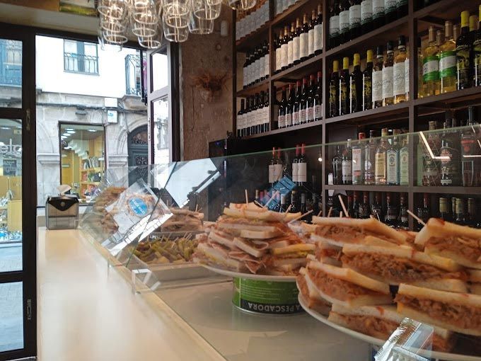 Un restaurante con exposición de sándwiches y botellas de vino.