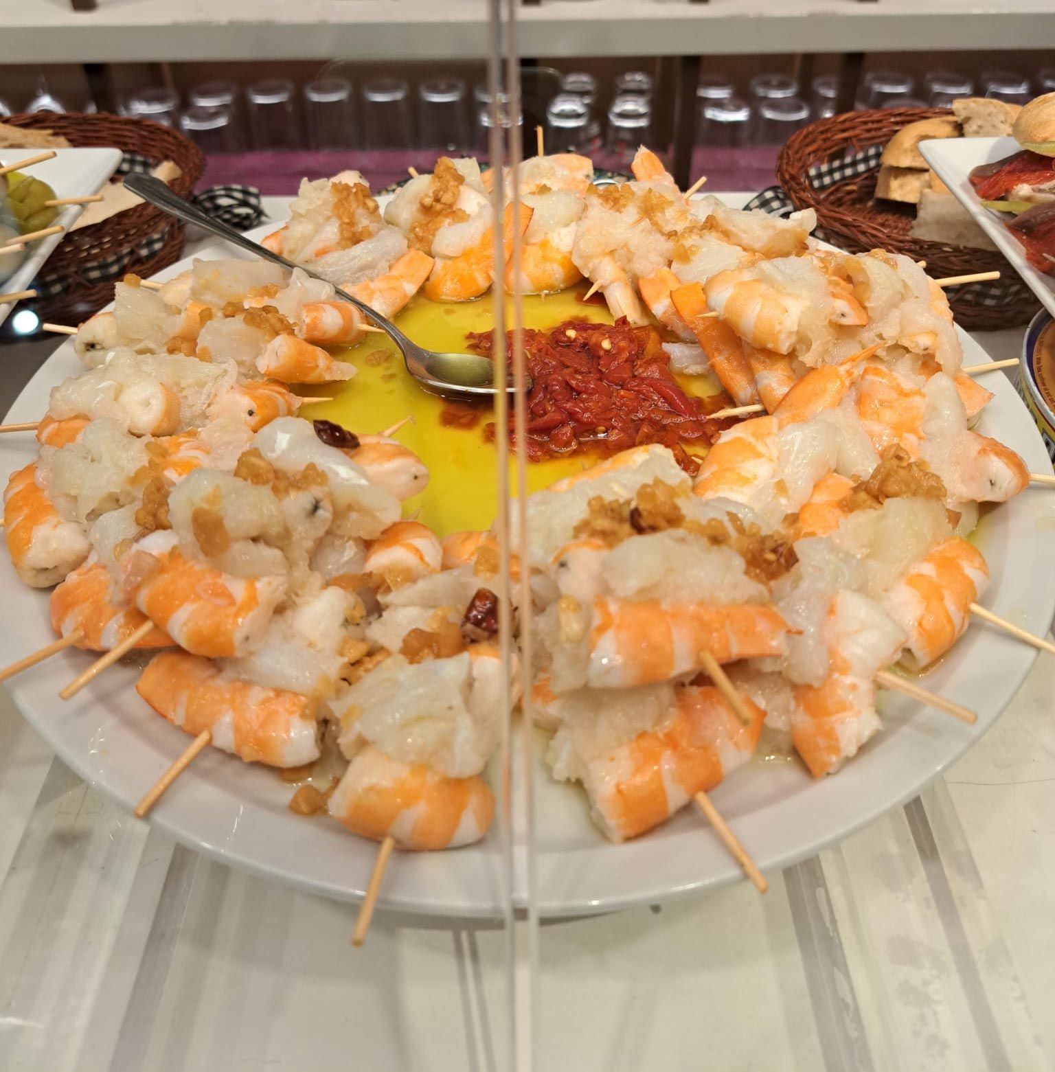 Un plato de camarones en brochetas con una cuchara en el medio