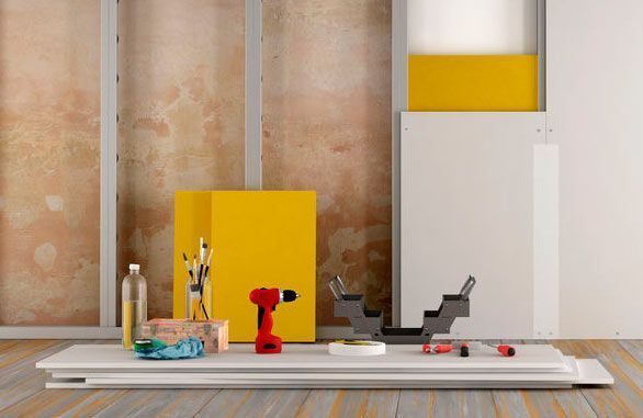 Una habitación con un taladro, herramientas y una pila de paneles de yeso.