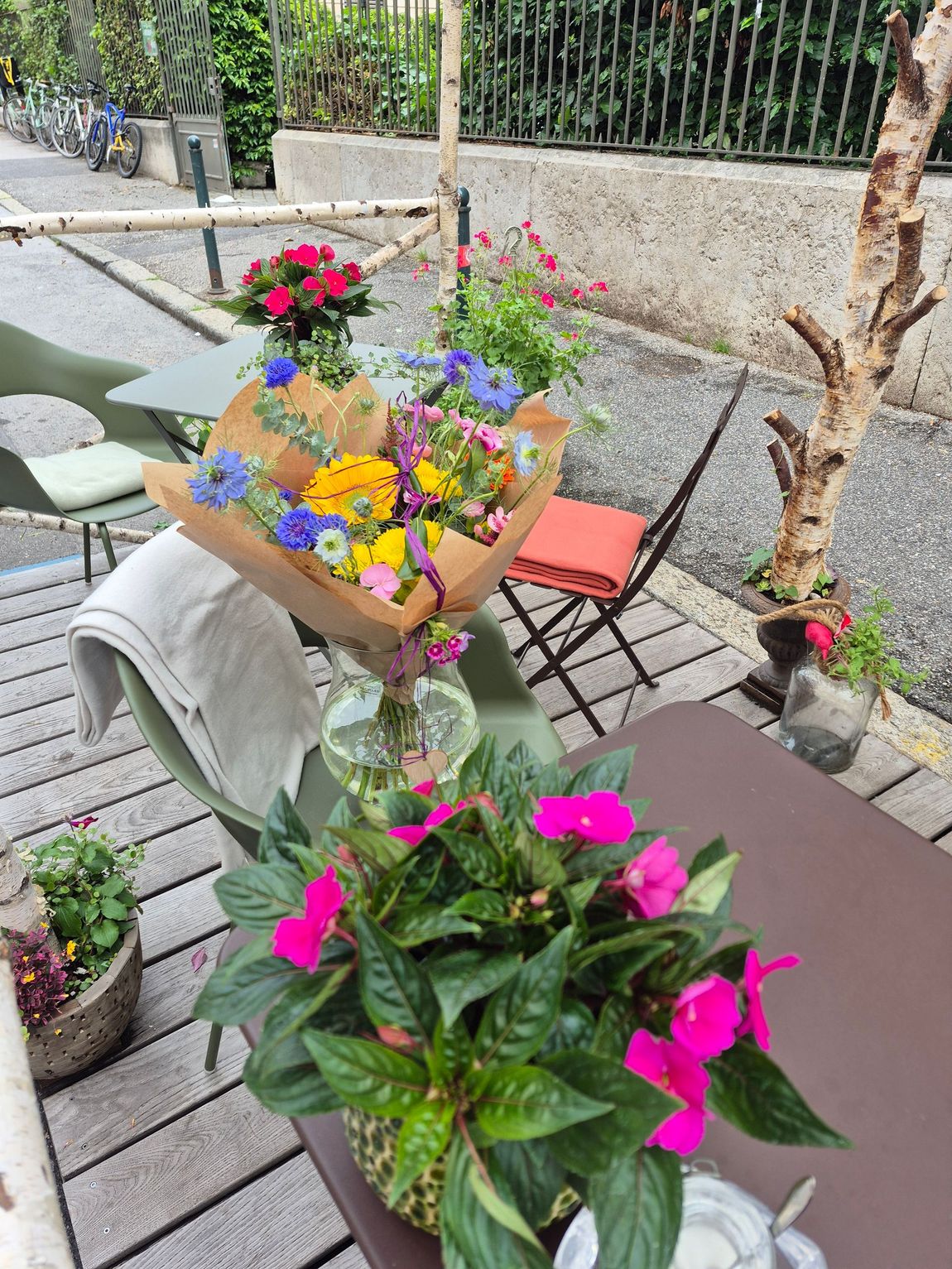 Fleurs rouges et roses en pots sur une étagère en bois dans un cadre de jardin