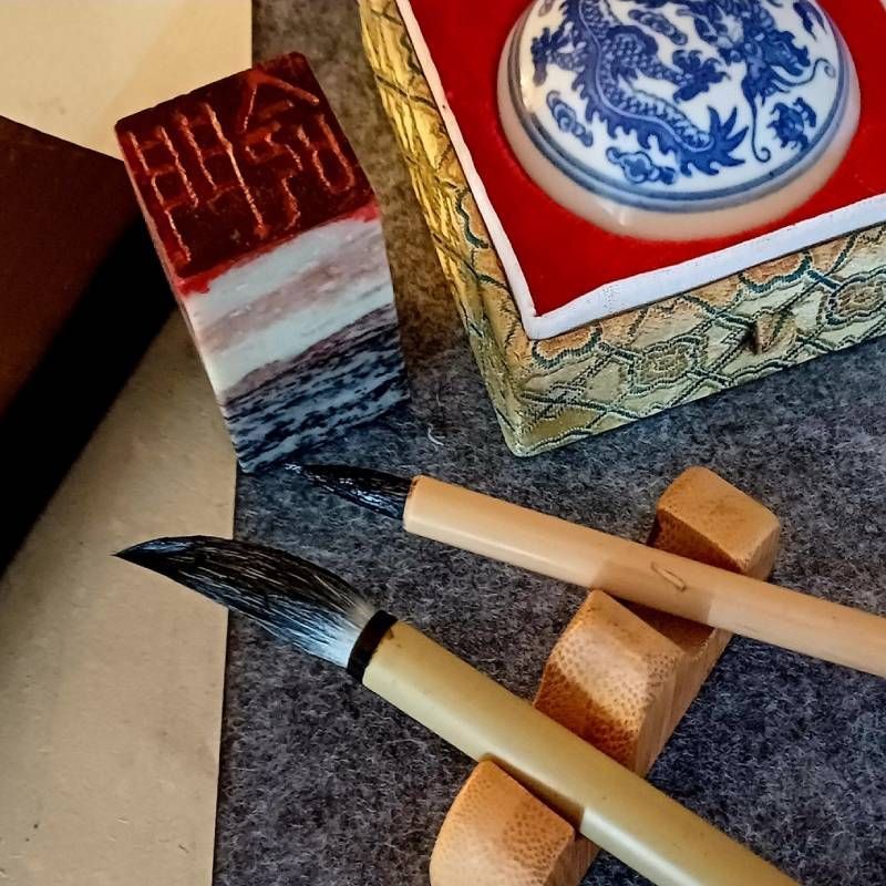 A box with a dragon on it sits next to a brush and a stamp