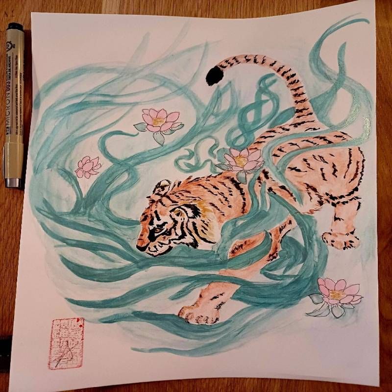 A drawing of a tiger is on a piece of paper next to a pen
