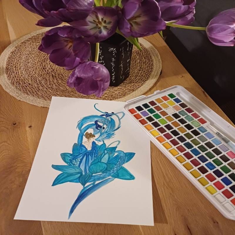 A painting of a flower next to a palette of watercolors