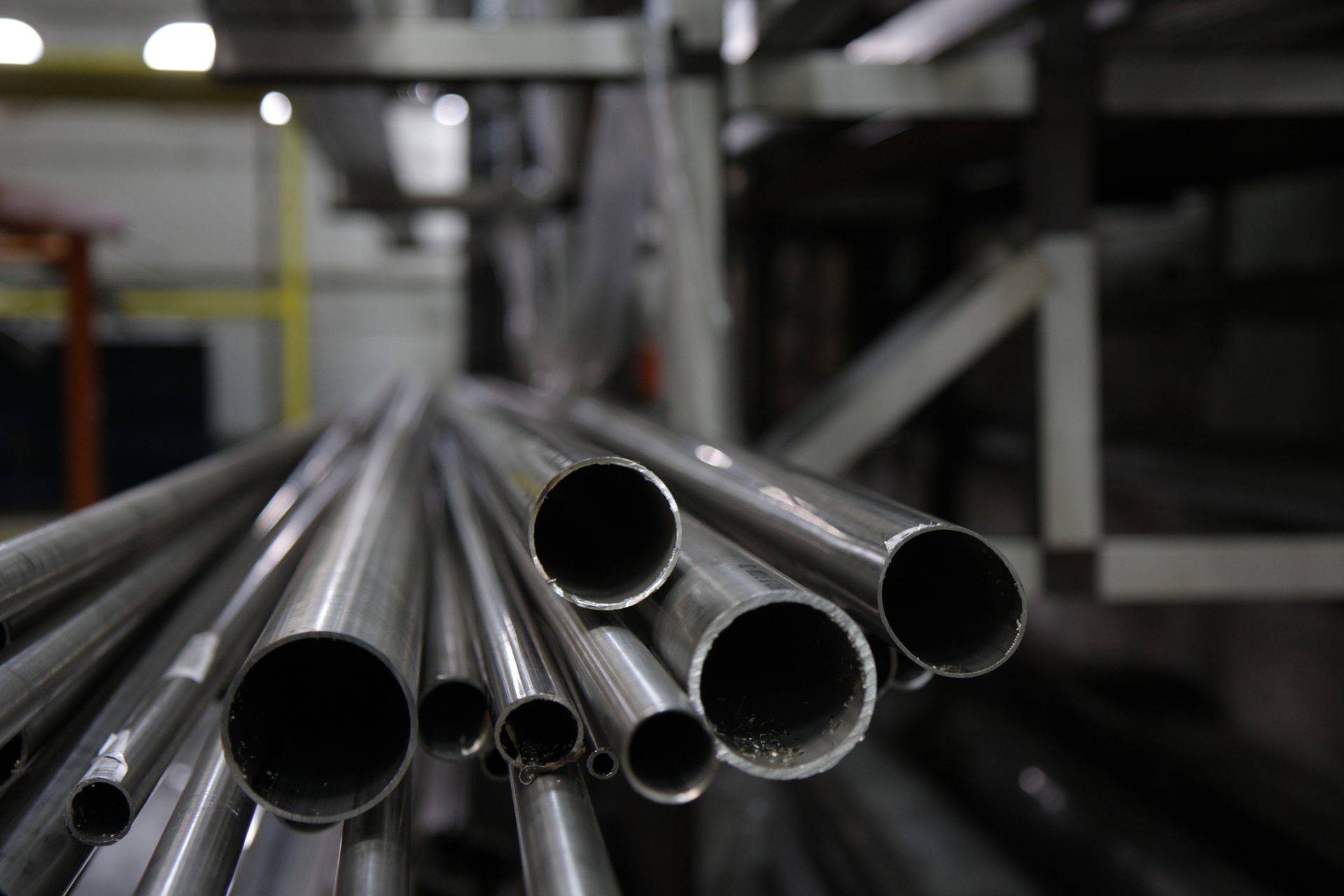 Tubes métalliques de différentes tailles, empilés dans un entrepôt.