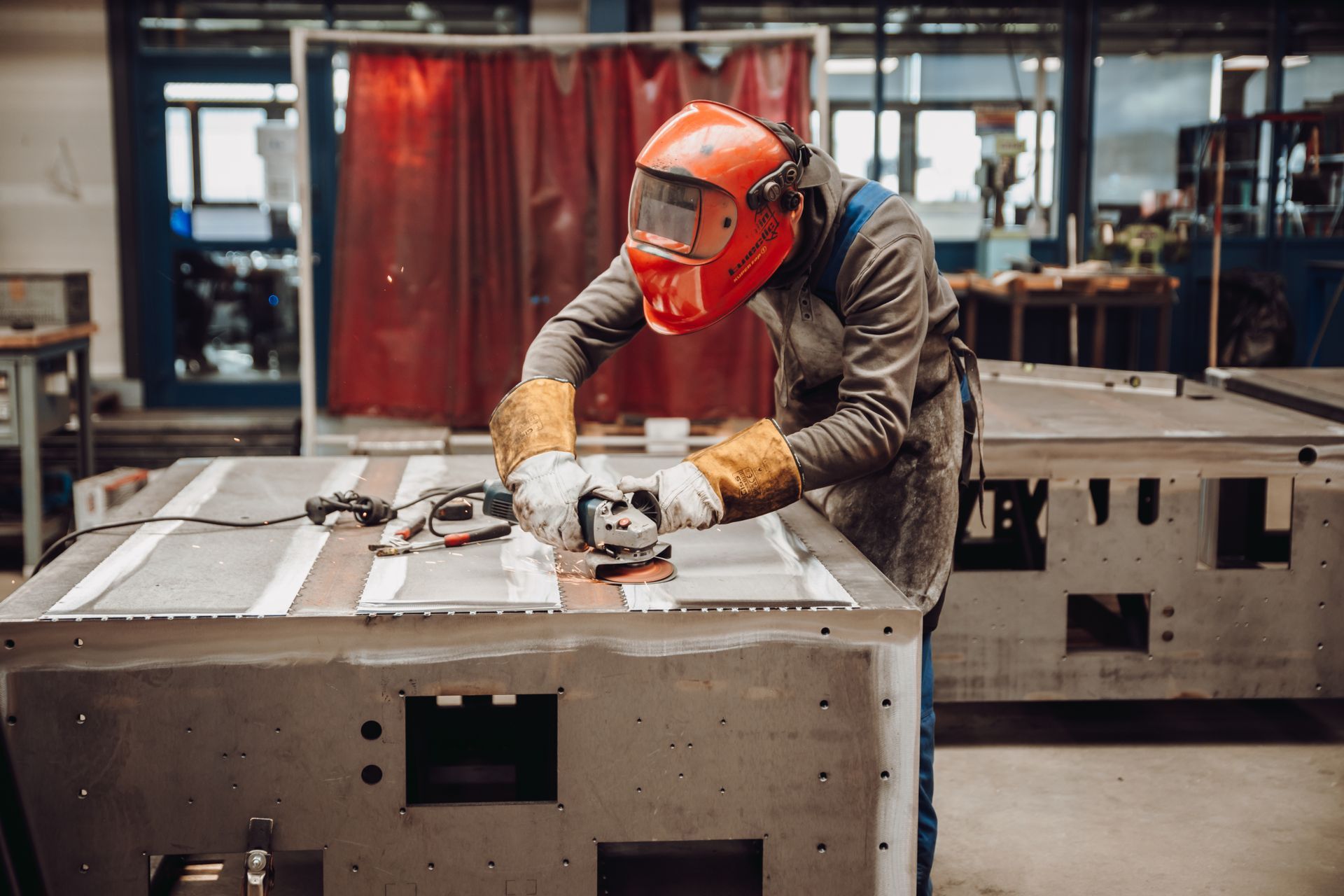 Ouvrier métallier qui effectue un surfaçage à la disqueuse