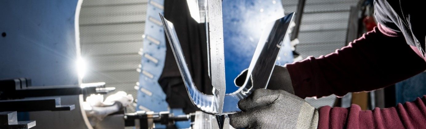Machine de découpe laser coupant une tôle, des étincelles sont visibles.