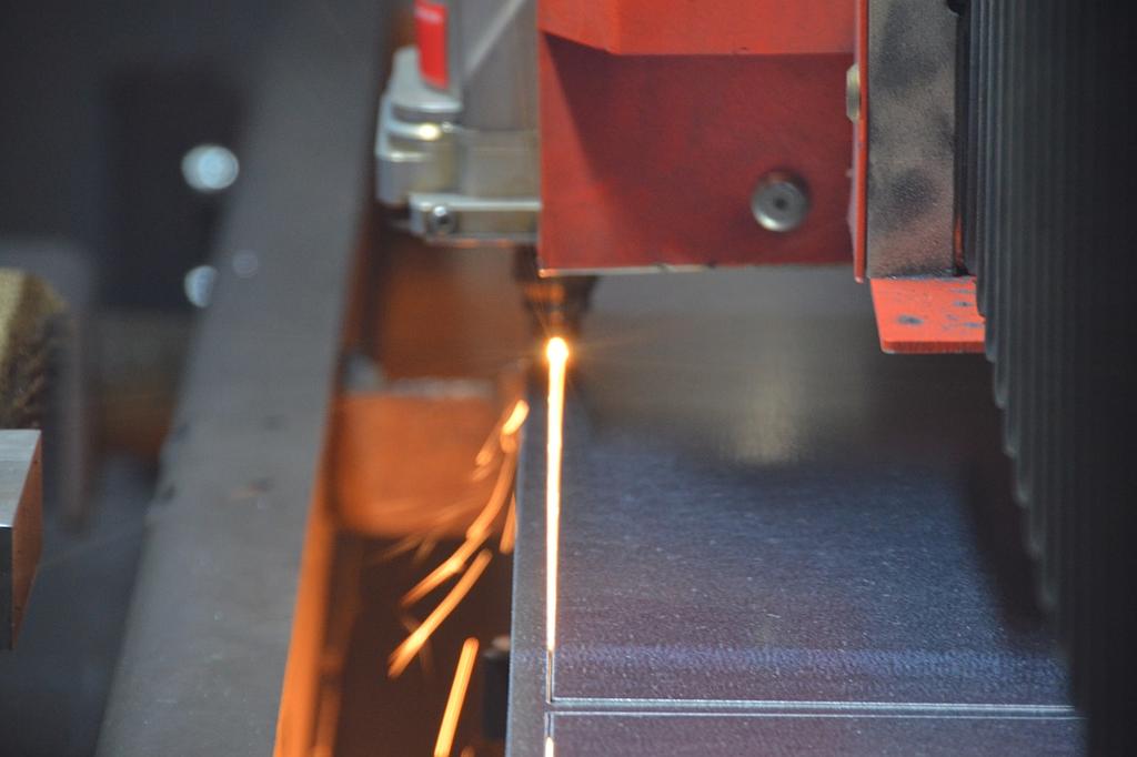Machine de découpe laser en action, projetant des étincelles sur une surface métallique