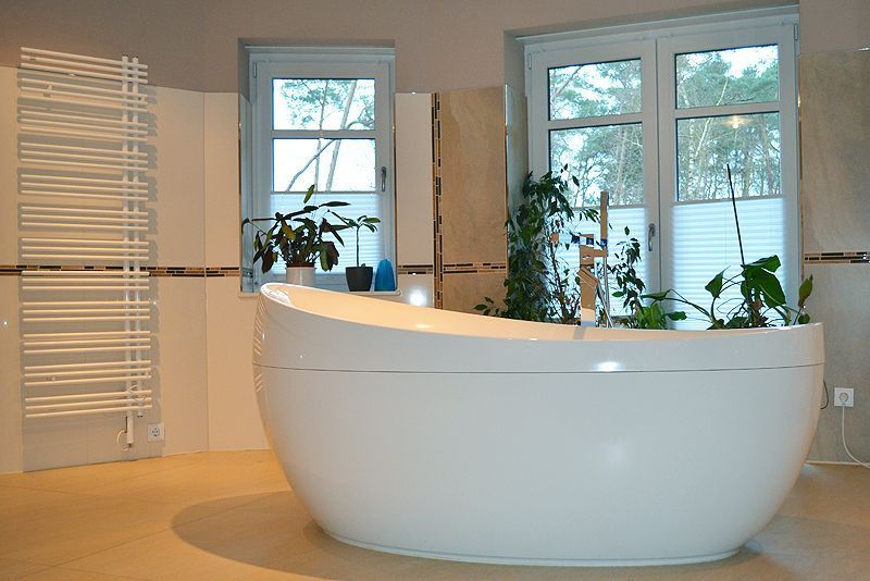 Eine weiße Badewanne in einem Badezimmer neben einem Fenster