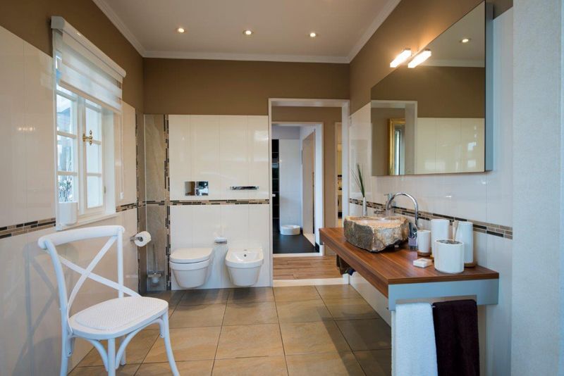 Ein Badezimmer mit Stuhl, Waschbecken, Toilette und Spiegel