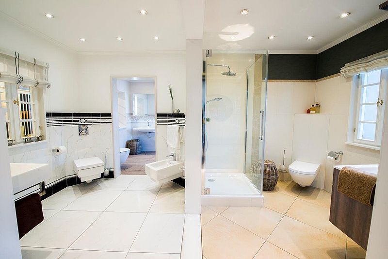 Ein Badezimmer mit ebenerdiger Dusche, Waschbecken, Toilette und Bidet.