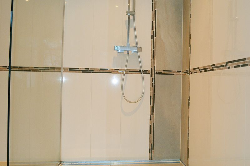 Ein Badezimmer mit ebenerdiger Dusche und Duschkopf.