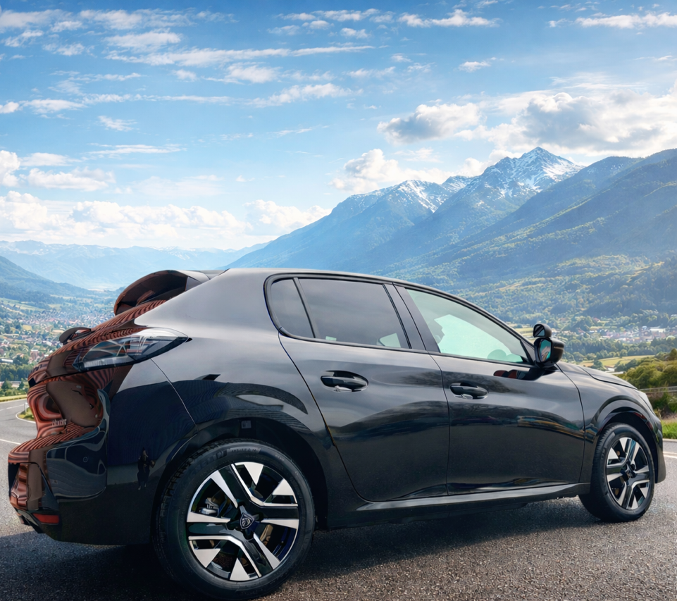 Voiture noire garée sur la route, avec des montagnes en arrière-plan.